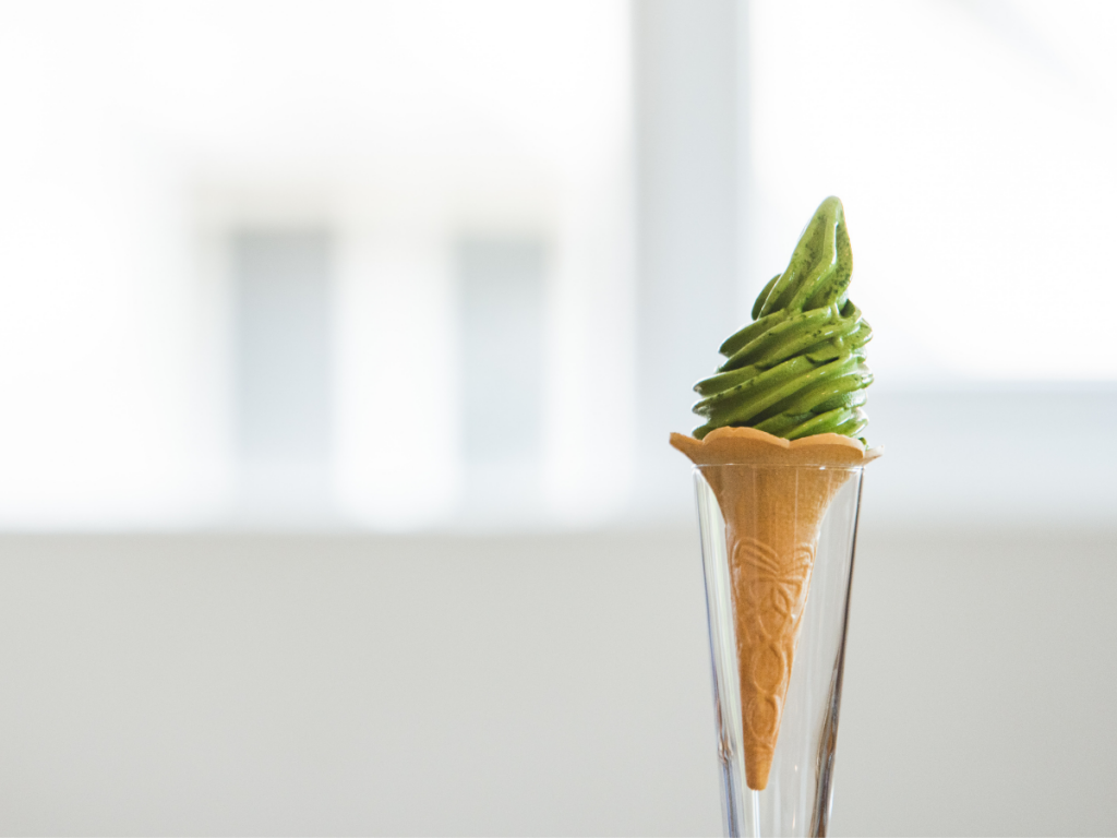 Vegan matcha ice cream in a soft serve ice cream cone
